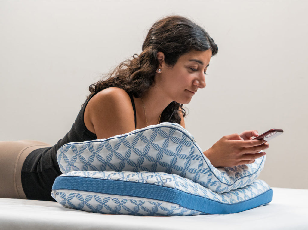 Woman using a smartphone while lying on Luxury cooling pillows
