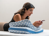 Woman using a smartphone while lying on Luxury cooling pillows
