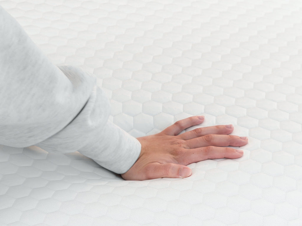 Hand pressing into the quilted cover of the 4 lb Memory Foam Mattress Topper.
