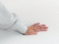 Hand pressing into the quilted cover of the 4 lb Memory Foam Mattress Topper.