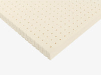 Angled view of a perforated Talalay latex mattress topper with ventilated hole pattern.